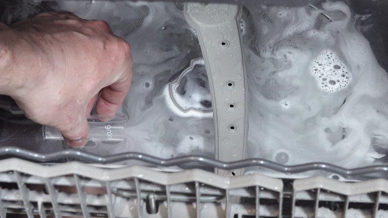 Maschine im laufenden Betrieb öffnen und Wasser aus dem Spülraum in den Messbecher füllen